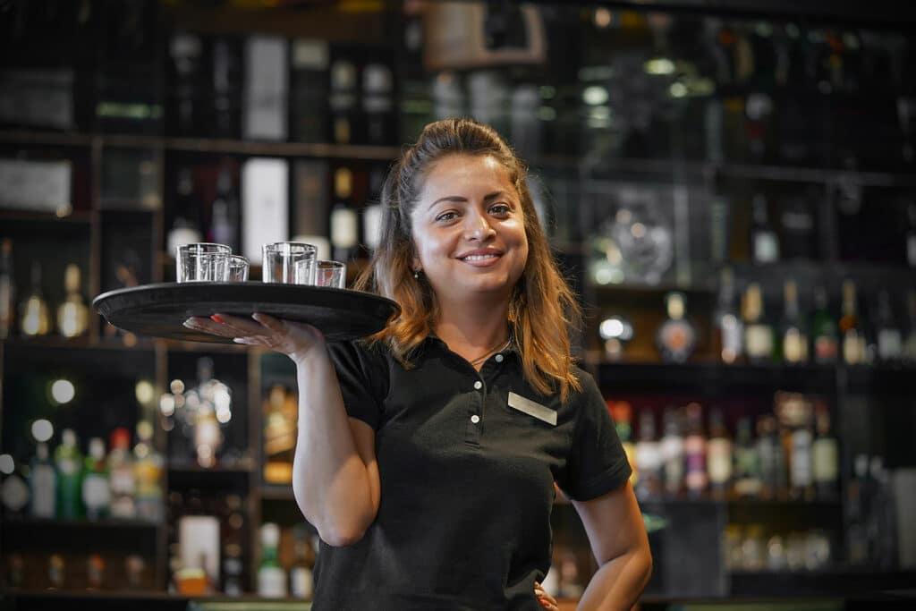 Waitress carries a whiskey glass on a tray in hotel restaurant